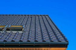 A vertical low angle closeup shot of the black roof of a building with a blue background